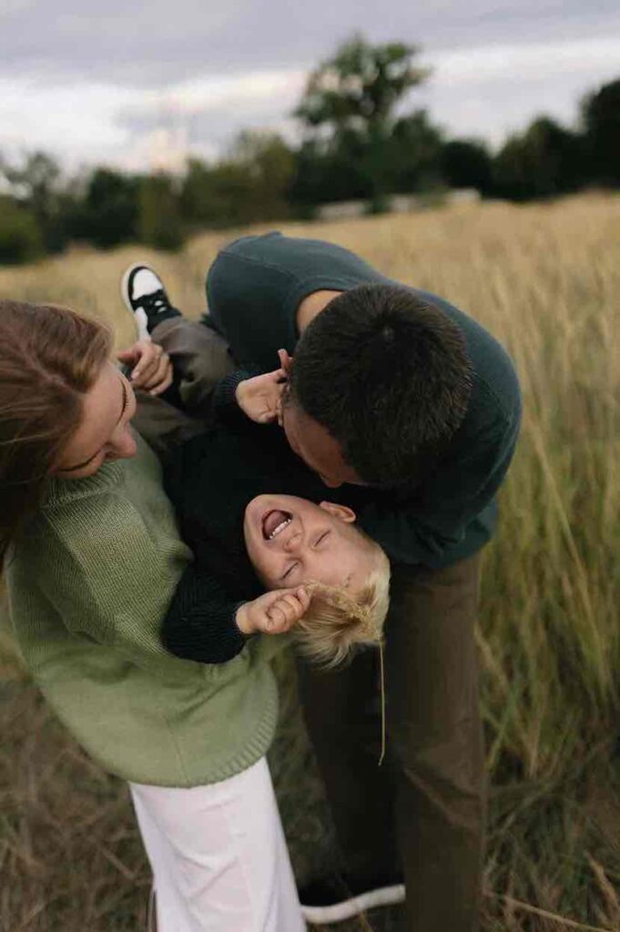 Mama und Papa halten lachenden blonden Jungen in den Armen