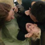 Mama und Papa halten lachenden blonden Jungen in den Armen